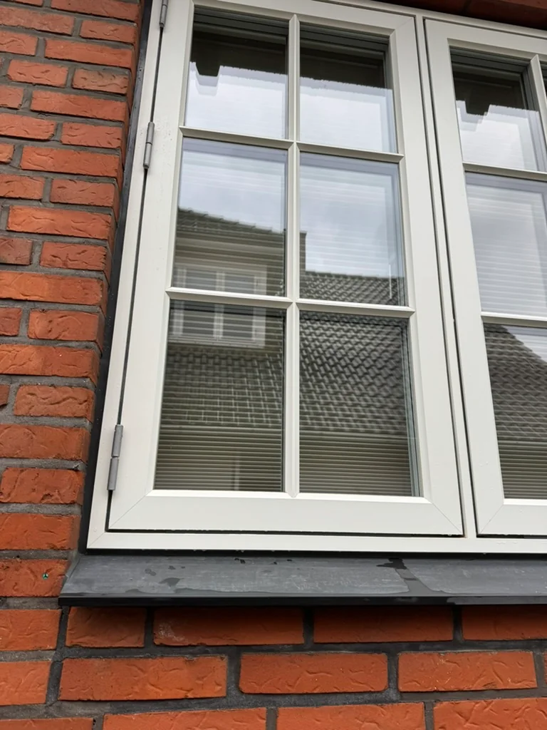 Hvid vinduesramme og sprosser efter nedvaskning, hvor det røde murstensstøv er fjernet.